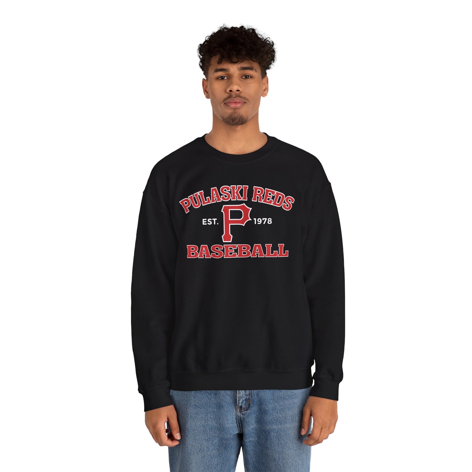 A person models the Printify P Reds Baseball Est. 1978 - Unisex Heavy Blend™ Crewneck Sweatshirt, featuring "Pulaski Reds Baseball Est. 1978" in red and white text, against a plain white background.