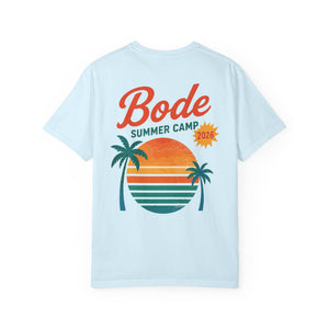 The BODE Summer Camp T-Shirt 2026 "Throwback Sunset" by Printify features "Bode Summer Camp 2026" text and a vibrant palm tree sunset graphic on a light blue Comfort Colors 1717 tee for a vintage-inspired, soft feel. Unisex fit.