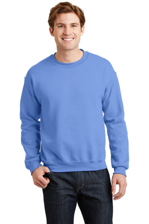A person wearing a blue Gildan Heavy Blend Crewneck Sweatshirt 18000 and jeans stands smiling.