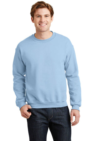 A person wearing a light blue Gildan Heavy Blend Crewneck Sweatshirt 18000 and dark jeans stands smiling against a white background.