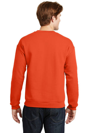 A person wearing a vibrant orange Gildan Heavy Blend Crewneck Sweatshirt 18000, crafted from a comfortable 50/50 cotton-polyester blend, pairs it seamlessly with dark jeans as they are captured from behind.