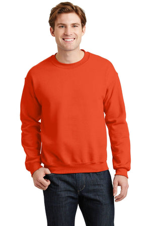 A person wearing a Gildan Heavy Blend Crewneck Sweatshirt 18000 in orange along with dark jeans smiles while standing against a plain white background.
