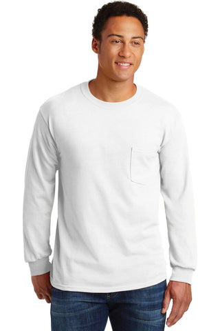 A man stands wearing a plain white Gildan Ultra Cotton 100% cotton long sleeve t-shirt with pocket (Pack of 36, style 2410, custom screen printed logo included) paired with blue jeans.