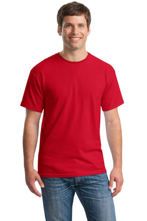 A man stands facing forward, smiling, wearing a Gildan Heavy 100% Cotton Custom T-Shirt (Gildan 5000) in red and blue jeans against a white background.