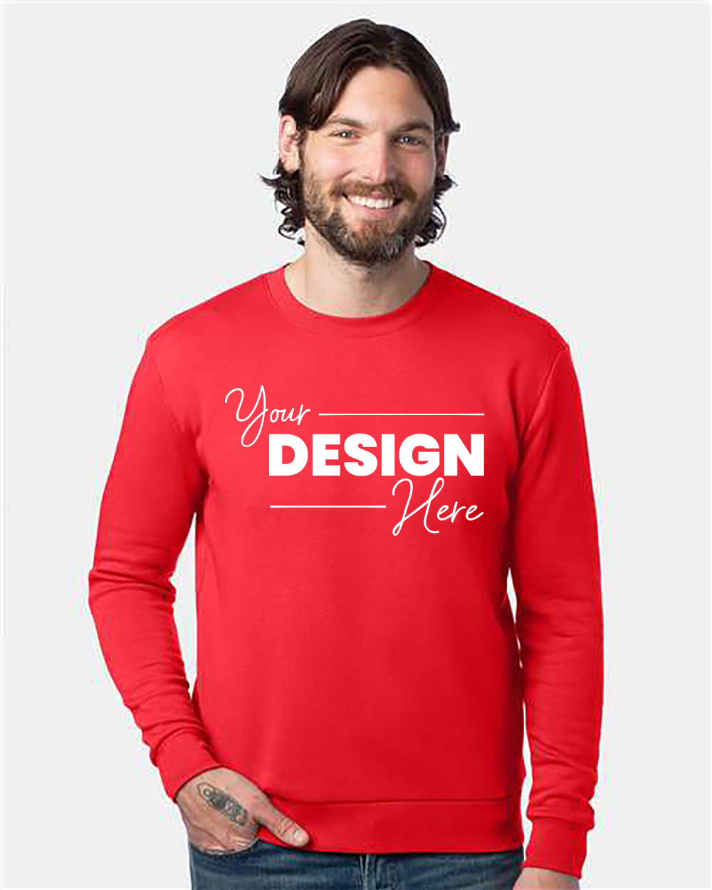 A smiling man with long hair and a beard is wearing an Alternative Eco-Cozy Fleece Crewneck Sweatshirt that says "Your Design Here" in white text. With one hand in his pocket, he stands against a plain white background.