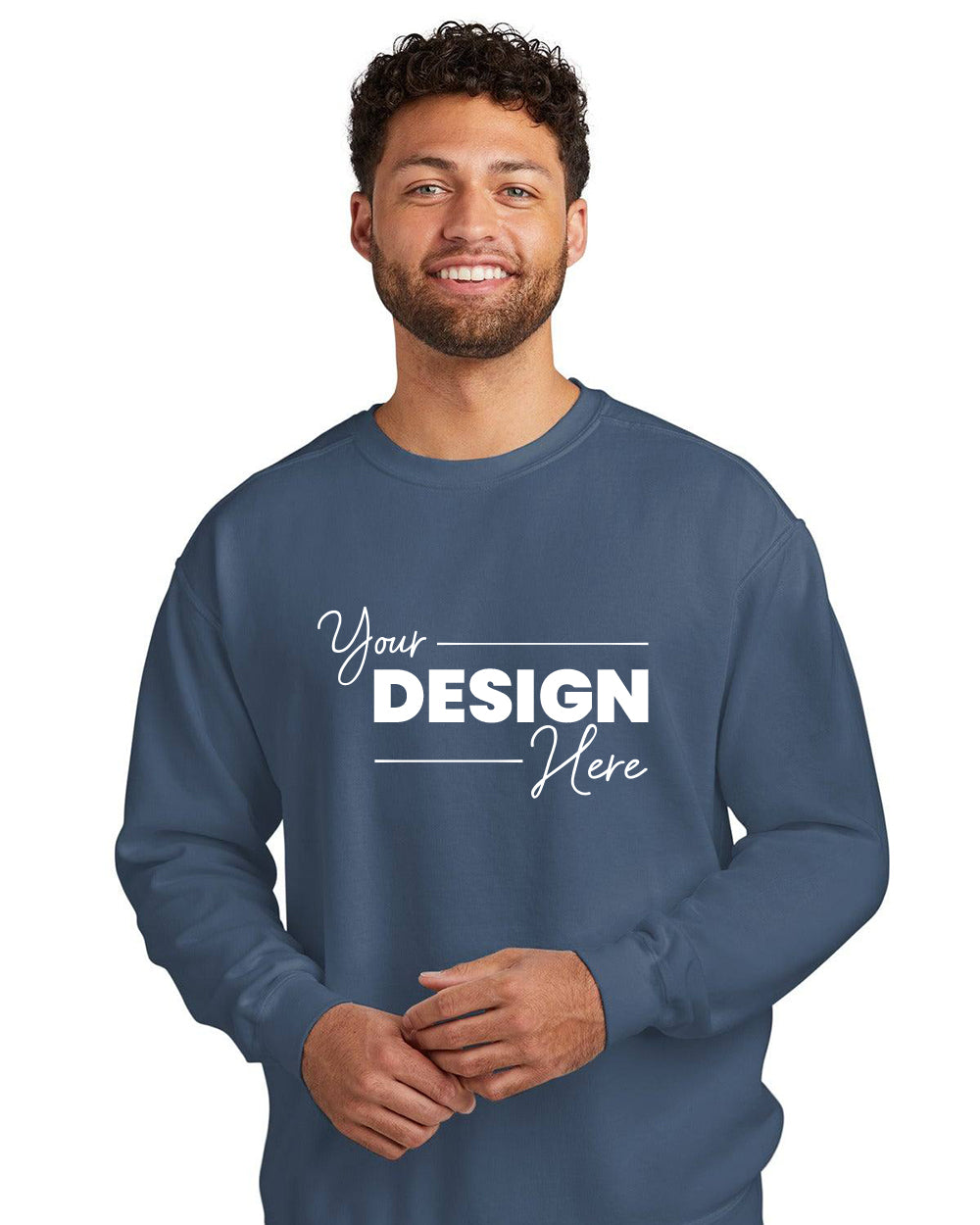 Someone is wearing a Comfort Colors Ring Spun Crewneck Sweatshirt 1566 in blue, featuring "Your Design Here" printed on the front and made from a cotton/poly blend.