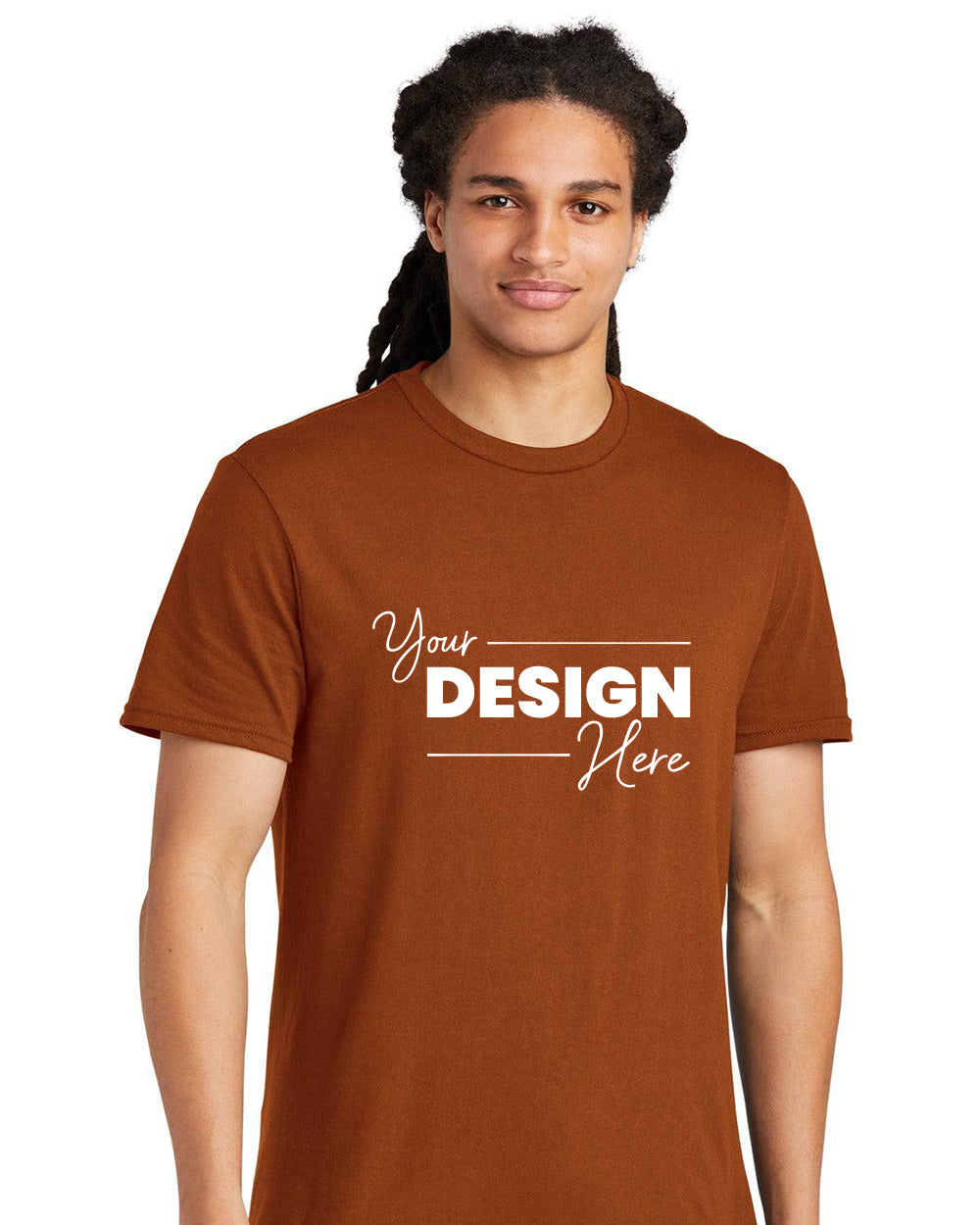 A person wearing a brown District The Concert Tee T-Shirt DT5000 with the text "Your Design Here" in white, made from soft spun cotton, stands against a plain white background.