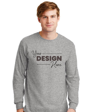 A man wears a Gildan 100% US Cotton Long Sleeve T-Shirt (Pack of 36), custom screen printed with "Your Design Here" in black on the front.