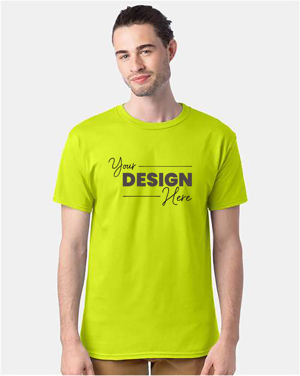 A man wearing a vivid green Hanes Essential-T T-Shirt Safety with the text "Your Design Here" printed on the front stands against a plain background.