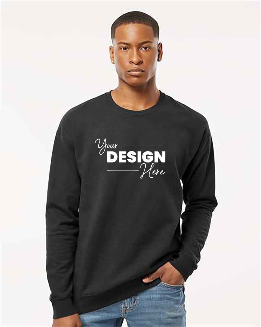 A person wearing a Tultex Unisex Fleece Crewneck Sweatshirt, featuring a high-quality blend in black with "Your Design Here" printed on the front, stands against a plain background.