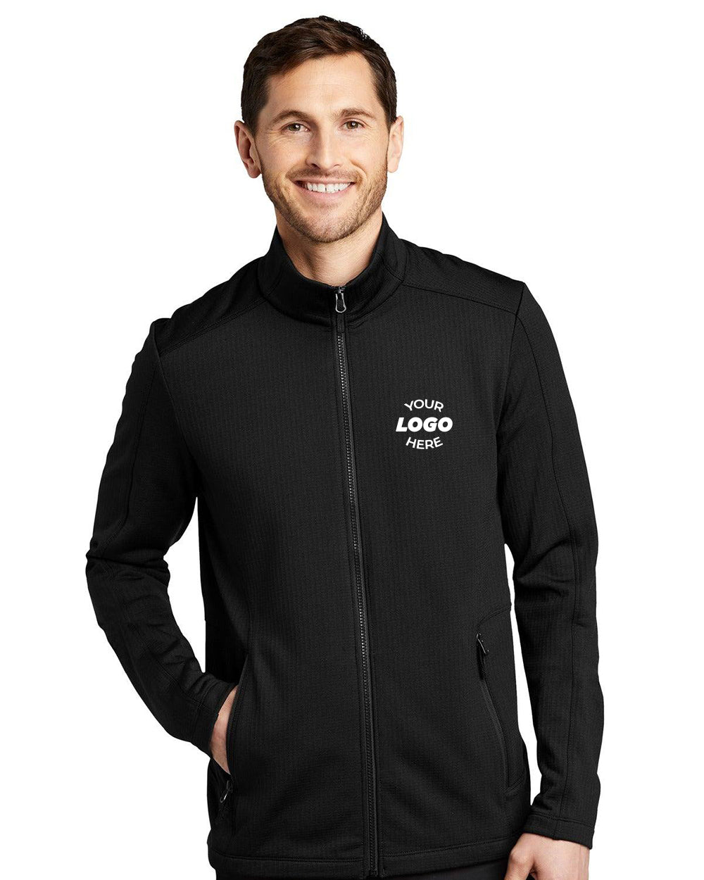 A person is smiling in the Port Authority Grid Fleece Jacket F239, a sleek black jacket with a zipper and customizable text on the chest. One hand rests comfortably in the pocket.
