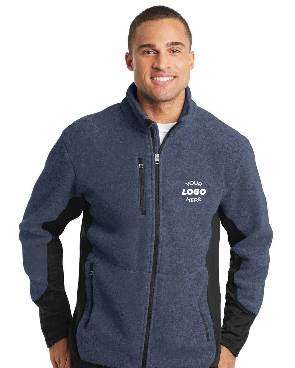 Man wearing a Port Authority R-Tek Pro Fleece Full-Zip Jacket F227 in blue and black, customized with "YOUR LOGO HERE" on the left chest, standing and smiling at the camera.