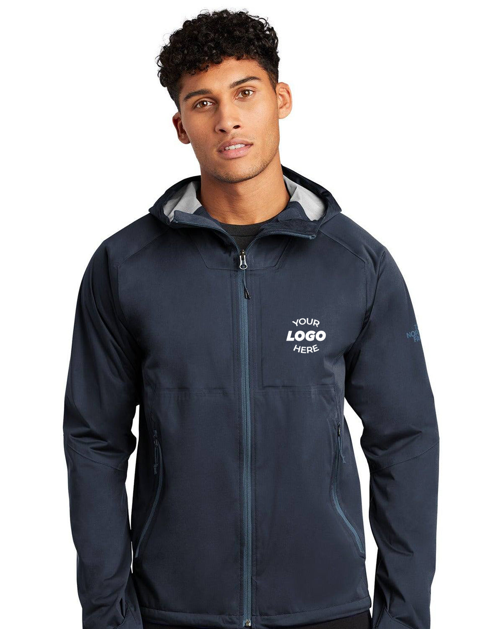 Individual wearing a navy The North Face All-Weather DryVent Stretch Jacket NF0A47FG with "Your Logo Here" on the chest, featuring an adjustable hood, looking at the camera.