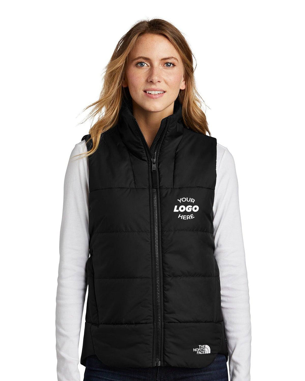 A woman wears a black The North Face Ladies Everyday Insulated Vest NF0A529Q over a white long-sleeve shirt. The WindWall polyester vest features "Your Logo Here" decoration on the left chest.