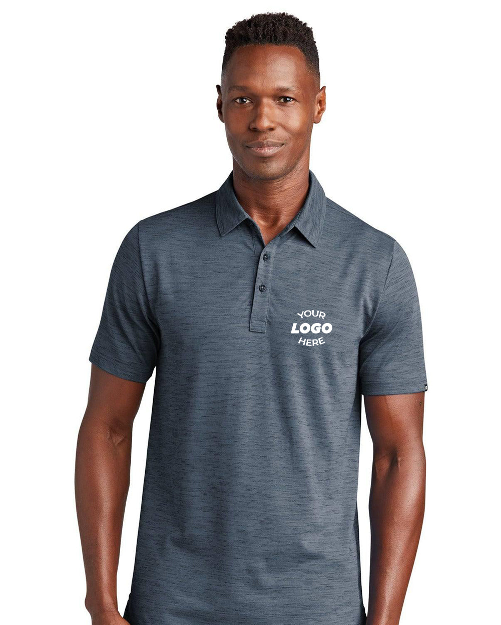 A man wears a TravisMathew Auckland Slub Polo TM1MW451 in dark gray, featuring short sleeves, a collar, quick-drying technology for all-day comfort, and a blank white chest area labeled "Your Logo Here.