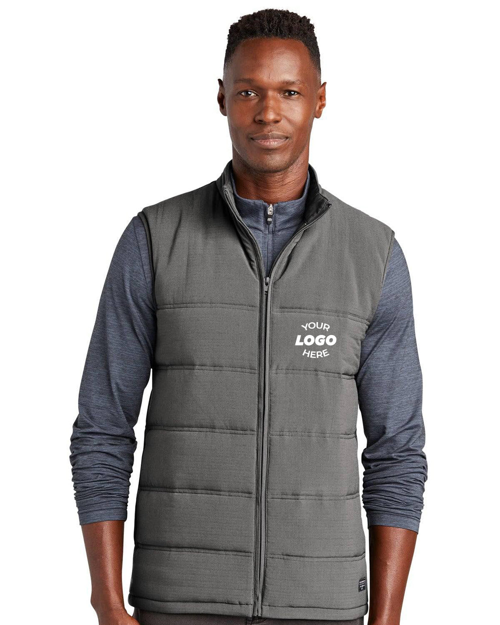 A man wears a TravisMathew Cold Bay Vest TM1MW453, a lightweight quilted puffer with 4-way stretch, over a long-sleeve shirt. "Your Logo Here" appears on the vest’s left chest.