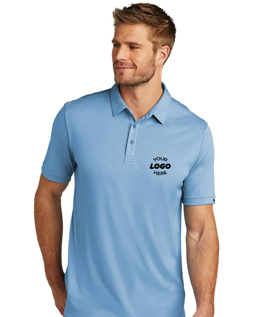 A man wearing a light blue TravisMathew Coto Performance Polo TM1MU410 with "Your Logo Here" printed on the left chest area.