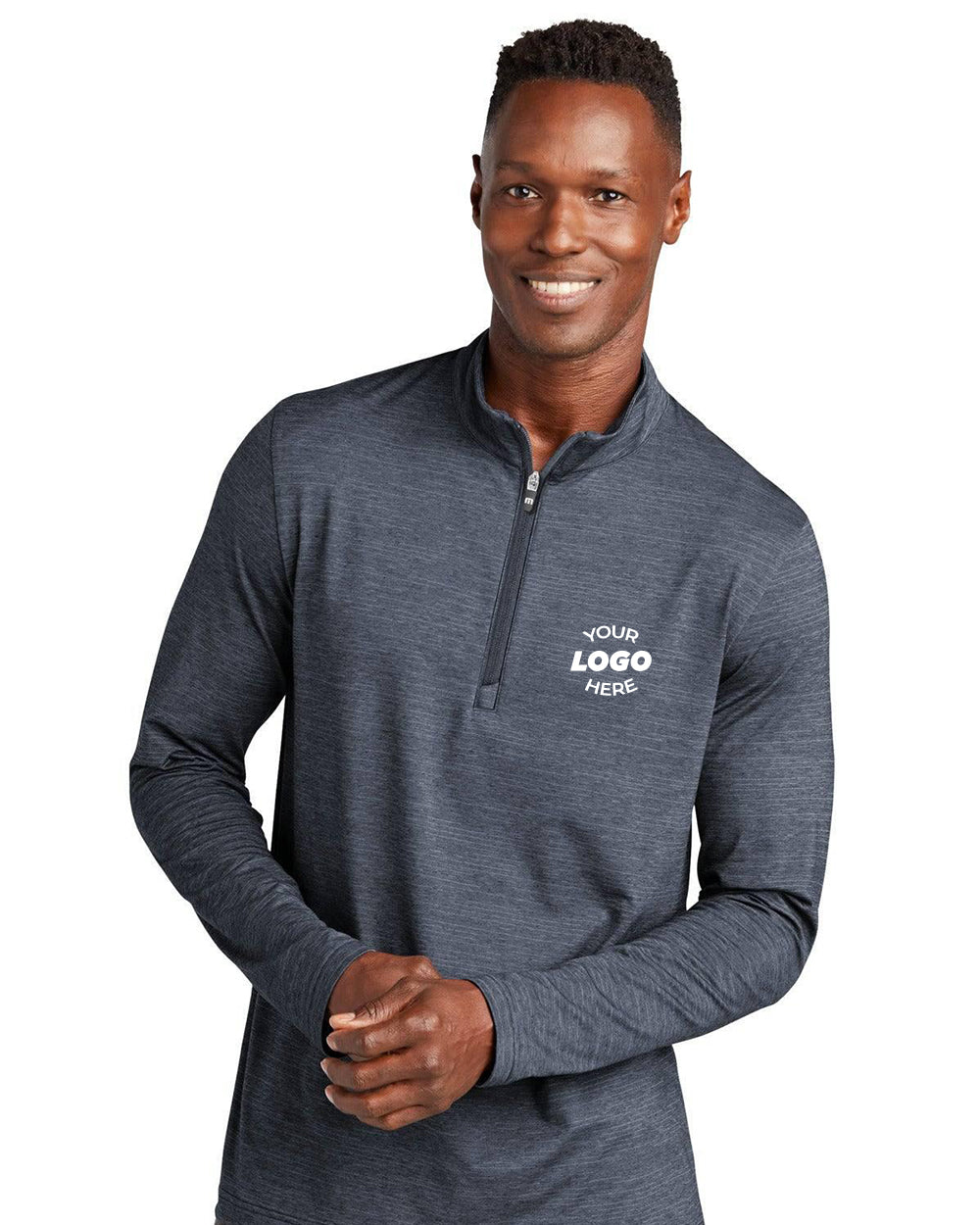 A man smiles with hands clasped, wearing the TravisMathew Crestview 1/4-Zip Pullover TM1MW452 in dark gray with “Your Logo Here” on the left chest, standing against a white background.