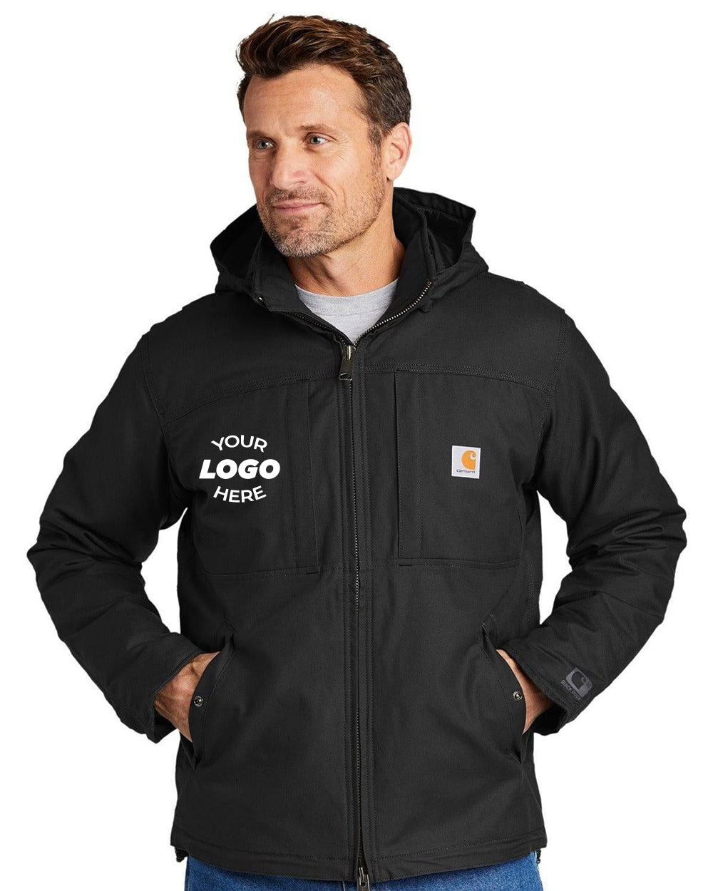 A man wearing a black Carhartt CT102207 Full Swing Cryder Jacket, hands in pockets, stands against a plain background. Featuring a logo placeholder on the chest, this durable workwear piece made from Quick Duck canvas combines style and functionality.