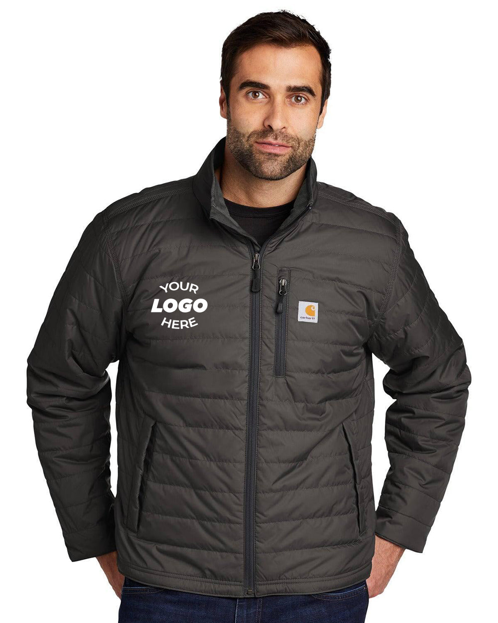 A man models the Carhartt Gilliam Jacket CT102208, featuring a dark, insulated design with a customizable logo patch on the chest. This jacket boasts a durable Cordura shell and innovative Rain Defender technology, set against a plain backdrop.
