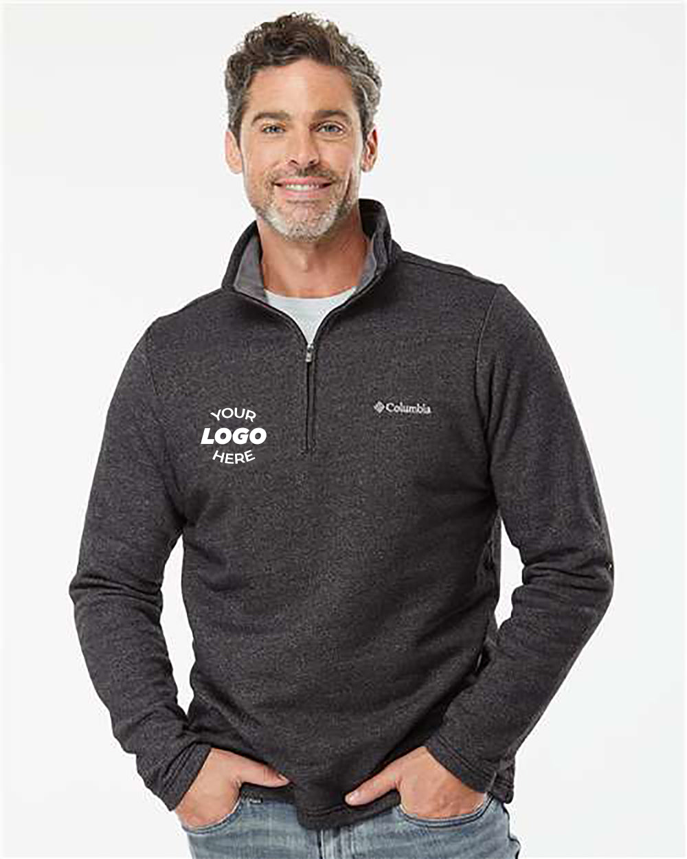 A man stands against a plain background, modeling a dark gray Columbia Great Hart Mountain III Half-Zip Pullover featuring "Your Logo Here" on the chest. This versatile workwear piece from Columbia is perfect for maintaining both style and comfort in any setting.