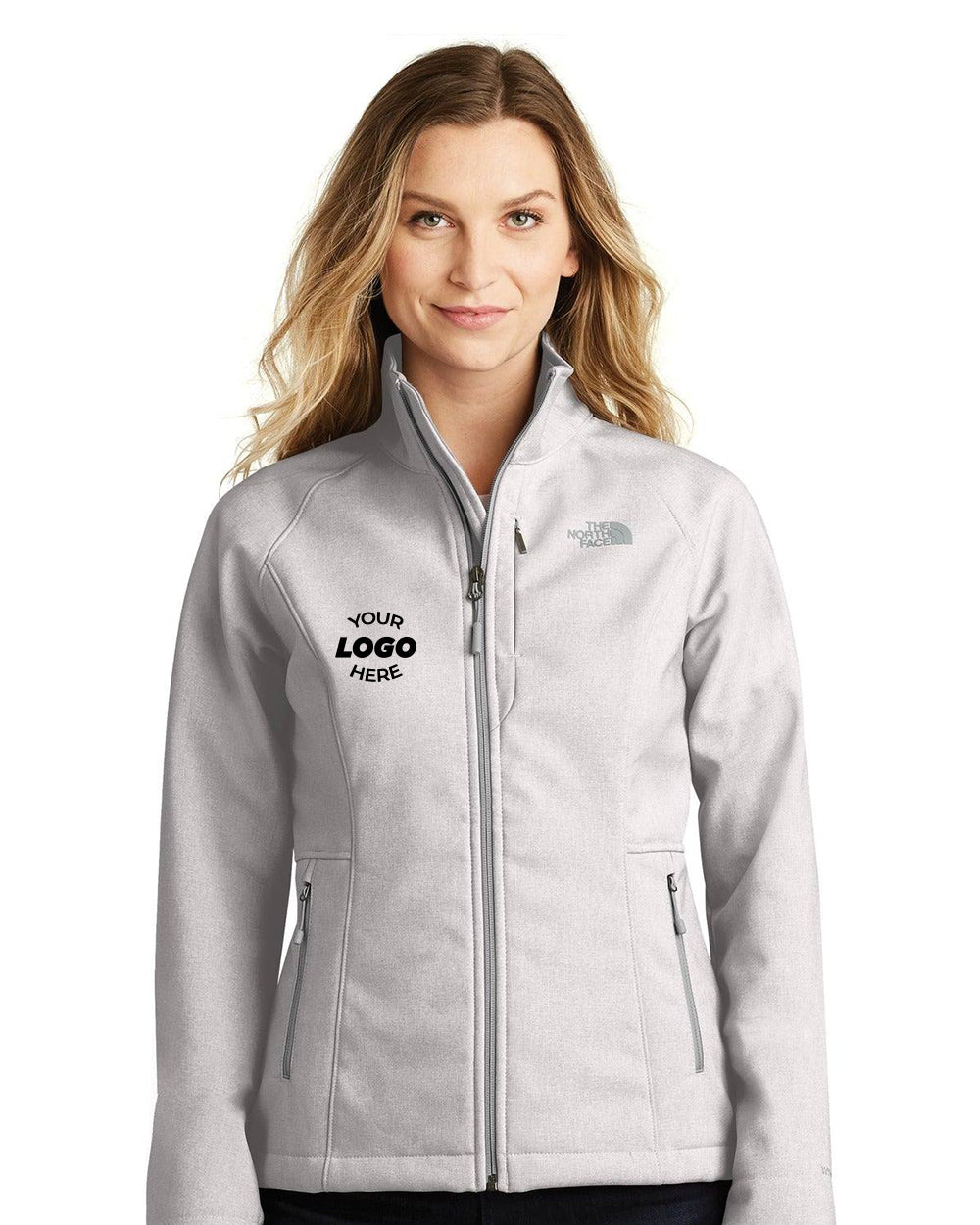 Someone is wearing The North Face Ladies Apex Barrier Soft Shell Jacket NF0A3LGU in light gray, featuring a customizable front left logo. This windproof jacket is designed to keep you warm and dry with its DWR finish.