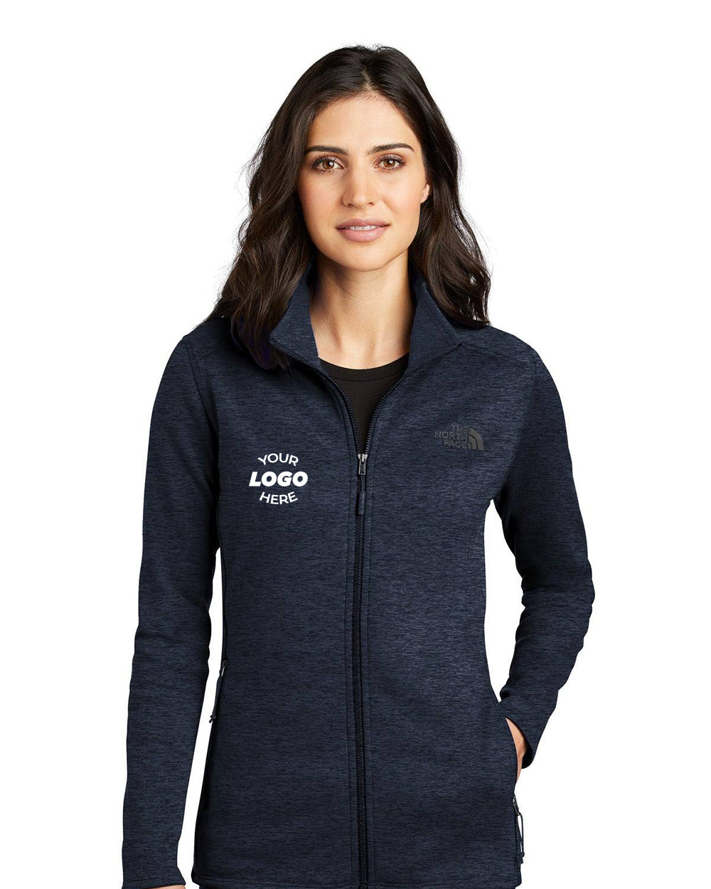 A woman wears The North Face Ladies Skyline Full-Zip Fleece Jacket (NF0A7V62) with "YOUR LOGO HERE" on the left chest, standing against a white background.
