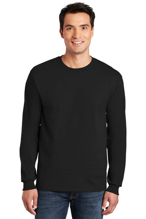 A man stands facing forward in a plain black Gildan 2400 Long Sleeve T-Shirt, made from 100% US cotton with custom screen printed logo included, and blue jeans, against a white background.