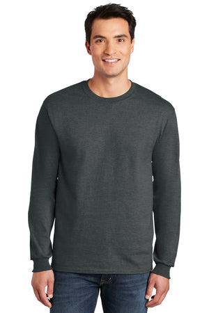 A man smiles facing forward, wearing blue jeans and a charcoal gray Gildan 2400 long-sleeve crew neck—made from 100% US cotton, with a custom screen printed logo included (Pack of 36).