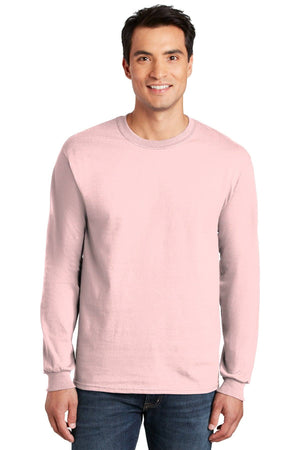 A man in a light pink Gildan 100% US Cotton Long Sleeve T-Shirt (Pack of 36, style 2400, custom screen printed logo included) and blue jeans stands facing forward, smiling.
