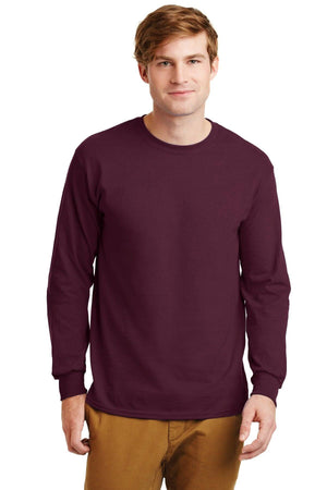 A man faces forward in a plain setting, wearing tan pants and a maroon Gildan 2400 long-sleeve crewneck shirt made from 100% US cotton, featuring a custom screen-printed logo.