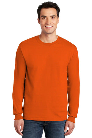 A man is wearing a Gildan 100% US Cotton Long Sleeve T-Shirt 2400 with a custom screen printed logo and blue jeans, standing against a white background.