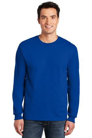 A man wearing a Gildan 100% US Cotton Long Sleeve T-Shirt (Pack of 36, style 2400) with custom screen printed logo and jeans, smiling at the camera against a white background.