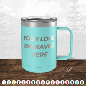 A TODAY ONLY - Custom Logo Drinkware Sale turquoise insulated tumbler with a handle and a steel rim, featuring the text "your custom logo engraved here" on a wooden surface, with a faded forest background. Designed by Kodiak Coolers.