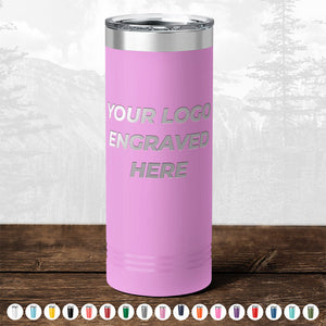 Pink insulated tumbler from Kodiak Coolers with "your logo engraved here" text displayed on a wooden surface against a blurred forest backdrop, perfect as a promotional gift. Multiple color options shown below.