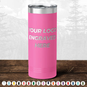 Pink insulated tumbler from Kodiak Coolers with "your logo engraved here" text, displayed as a promotional gift with optional color choices below, against a blurred forest background.