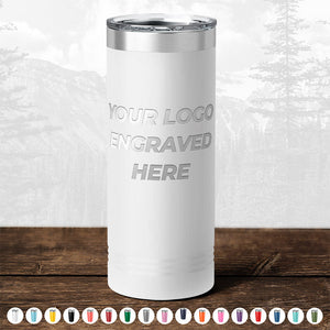 White insulated tumbler with a custom logo engraving option displayed on a wooden surface, with a blurred forest background. Get the TODAY ONLY - Hump Day Sale - Your Logo Engraved on Drinkware from Kodiak Coolers. Single Side Engraving Included in Price - Slider Lids Included