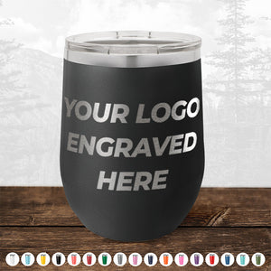 A black, stainless steel tumbler from Kodiak Coolers, featuring the text "YOUR LOGO ENGRAVED HERE," is placed on a wooden surface. Various color options for these personalized mugs are displayed below the tumbler, making it an ideal promotional gift during the HUGE LABOR DAY SALE - ENDS TODAY!