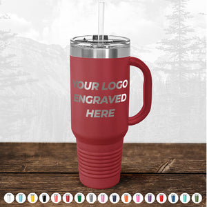 Red Kodiak Coolers insulated travel mug with a handle and straw, featuring the text "your custom logo engraved here", against a misty forest background.