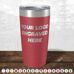 A red insulated tumbler with "your logo engraved here" text, perfect as a promotional gift, displayed on a wooden surface against a blurred forest background from Kodiak Coolers. Today only - Custom Logo Drinkware Sale - Your Logo Laser Engraved INCLUDED in Price - No Hidden Fee's