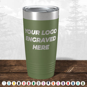 Green insulated tumbler with "your logo engraved here" on it, displayed on a wooden surface against a blurred forest background, perfect as a promotional gift from Kodiak Coolers - TODAY ONLY - Hump Day Sale - Your Logo Engraved on Drinkware - Single Side Engraving Included in Price - Slider Lids Included.
