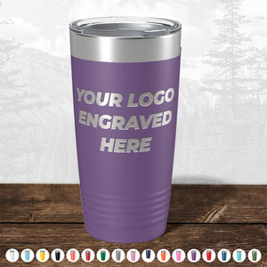 A purple insulated tumbler with "TODAY ONLY - Custom Logo Drinkware Sale - Your Logo Laser Engraved INCLUDED in Price - No Hidden Fee's" text, displayed on a wooden surface against a faded forest background by Kodiak Coolers.