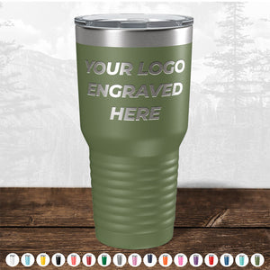 A green insulated tumbler from Kodiak Coolers with "your custom logo engraved here" text, displayed on a wooden surface with a faded forest background.