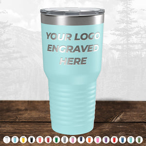 A customizable TODAY ONLY - Hump Day Sale - Your Logo Engraved on Drinkware - Single Side Engraving Included in Price - Slider Lids Included travel mug by Kodiak Coolers, ideal as a promotional gift, displayed on a wooden table against a blurred forest background.