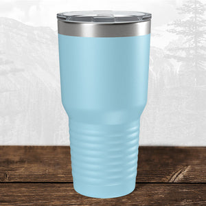 A Kodiak Coolers 30 oz tumbler featuring a laser-engraved Wisconsin Green Bay Bulldogs design rests on a wooden surface, with a subtle mountain landscape in the background.