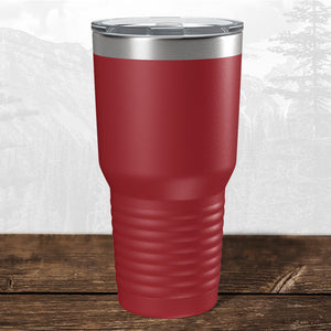 A Kodiak Coolers 30 oz red tumbler, laser engraved with the Wisconsin Luxemburg Casco Spartans school design and a clear plastic lid, sits on a wooden surface with a mountain background.