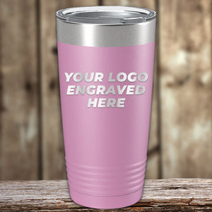 Pink insulated tumbler with "your logo engraved here" text, displayed on a wooden surface against a blurred wooden background, available at wholesale pricing. Get the Custom Tumblers 20 oz with your Logo or Design Engraved from Kodiak Coolers at special bulk wholesale pricing.