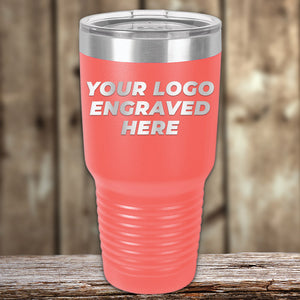 Kodiak Coolers Custom Tumbler in coral with a transparent lid, engraved with your logo—no setup fees & $200 minimum order. Perfect for custom mugs or promotional gifts, shown against a blurred wooden background.