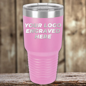 A pink Kodiak Coolers Custom Tumbler with a clear lid rests on a wooden surface, featuring "YOUR LOGO ENGRAVED HERE"—perfect for promotional gifts. No setup fees; $200 minimal order.
