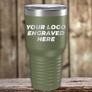 The green Kodiak Coolers Custom Tumbler with clear lid sits on wood, engraved with "YOUR LOGO ENGRAVED HERE"—ideal for personalized mugs or promo gifts. No setup fees, $200 minimal order.